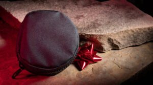 black nylon tactical bag on rocks with a red christmas bow